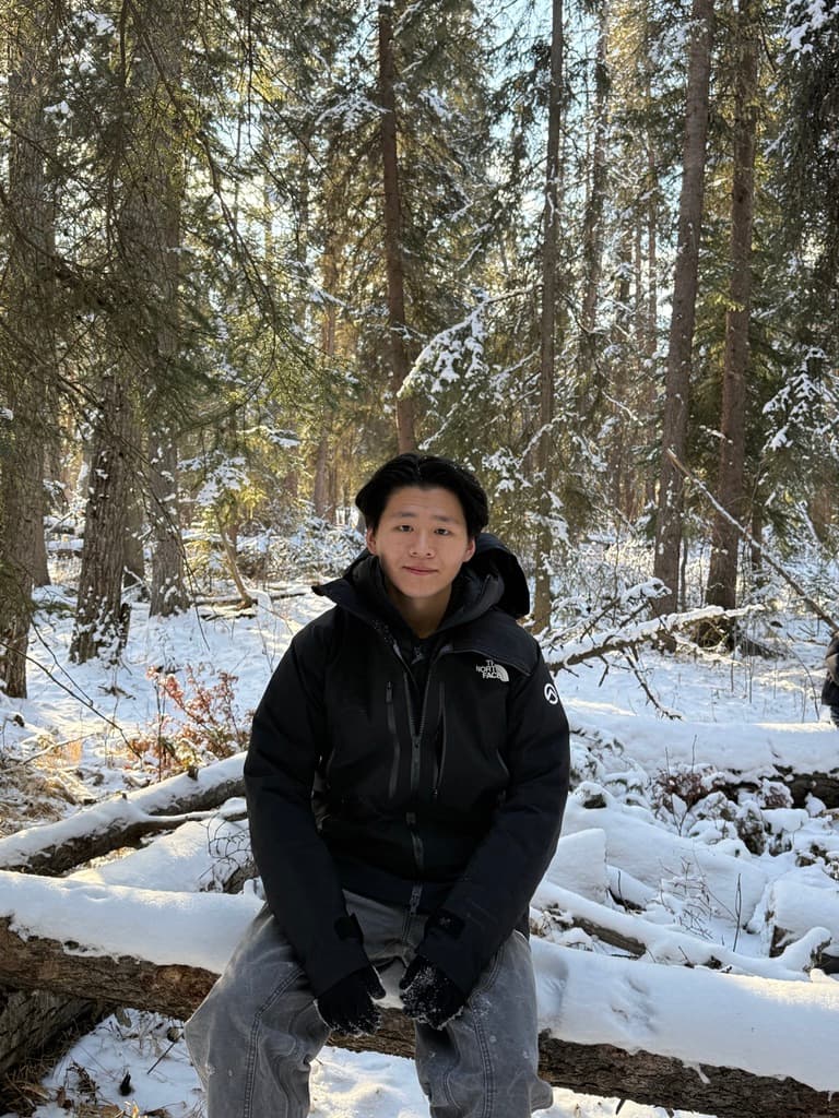 Junjie sitting in a snowy forest